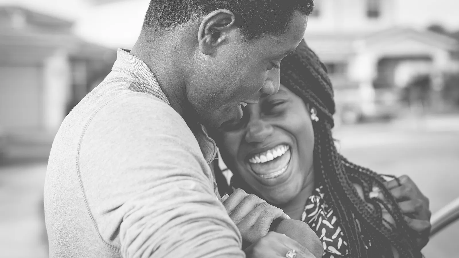 A Black couple laughing together in a warm embrace, in black and white